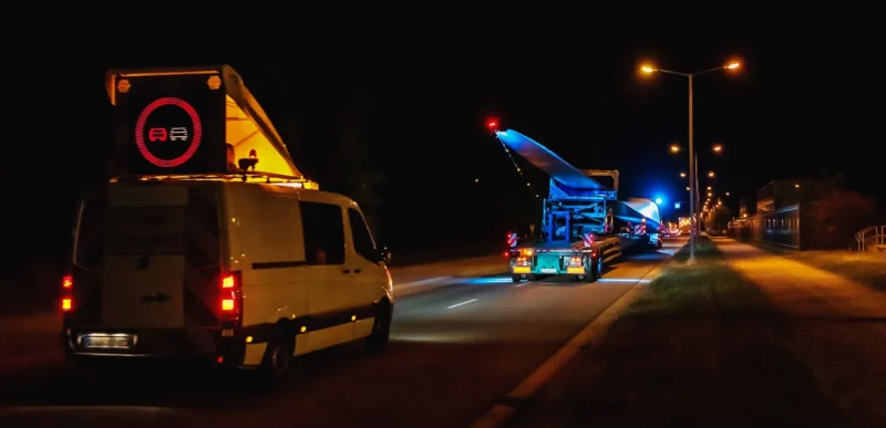 GAAC Begleitfahrzeug mit Wechselverkehrszeichenanlage sichert nachts einen Schwertransport mit Rotorblatt ab
