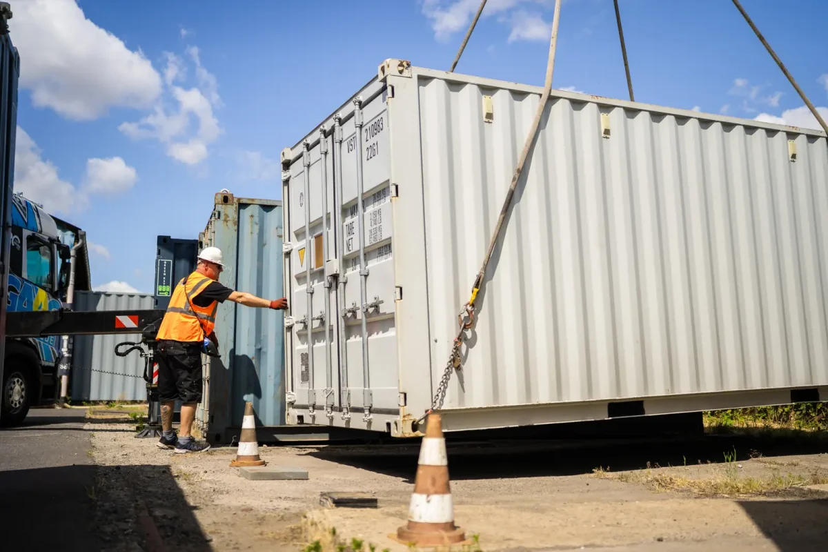 GAAC Mitarbeiter weist einen Container am Ladekran-LKW ein