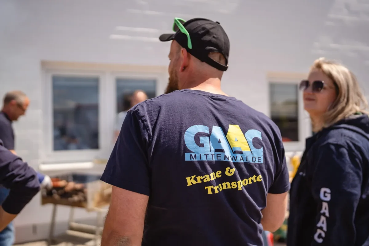 GAAC-Kollege im Firmenshirt Krane und Transporte mit Kollegen im Hintergrund