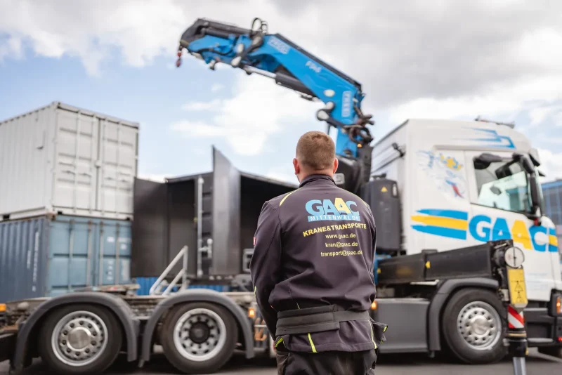 GAAC-Kollege im Firmenshirt vor dem Ladekran-LKW