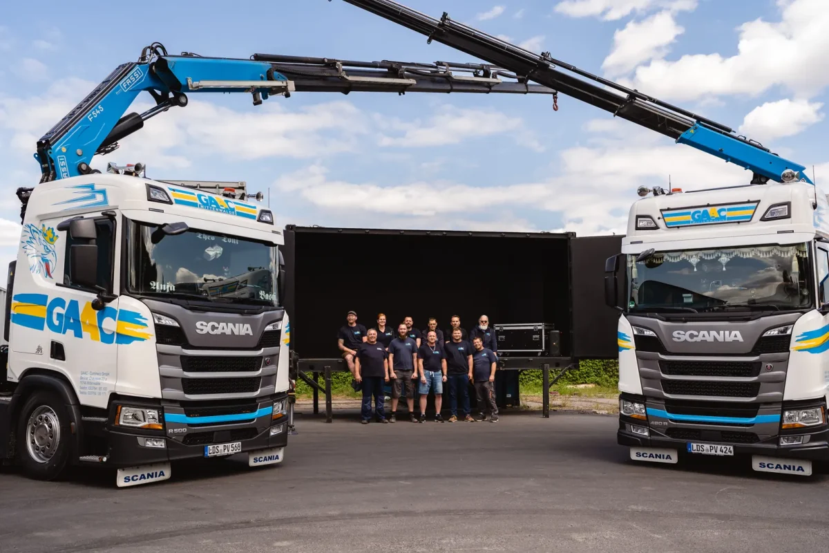 Das GAAC-Team zwischen zwei Scania-Ladekran-LKW auf dem Betriebshof